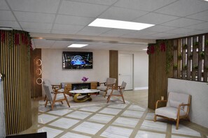 A modern hotel lobby with a central seating area, a television, and decorative plants. - Rodeway Inn Davenport-Champions Gate (Davenport)