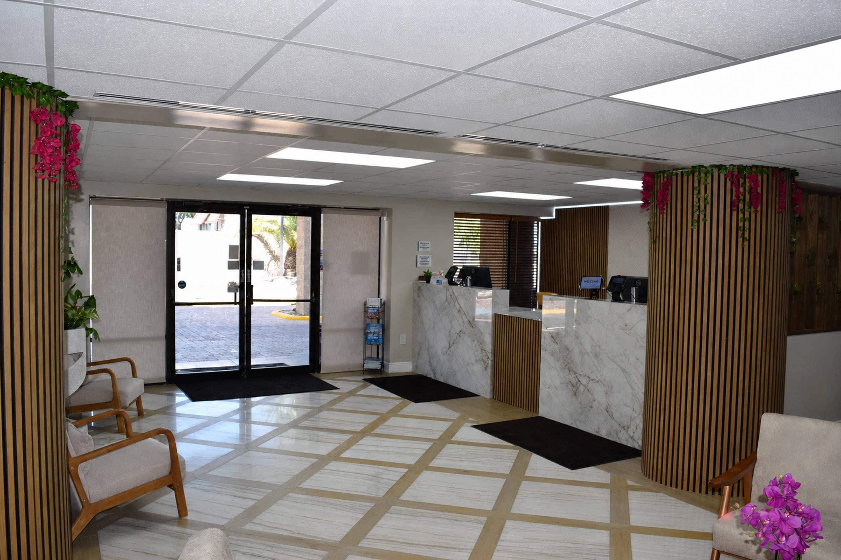 Una hall d'albergo con reception, area relax e vista attraverso le vetrate.