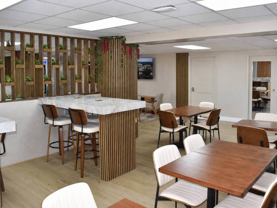 A modern dining area with a central island, wooden partitions, and white chairs.