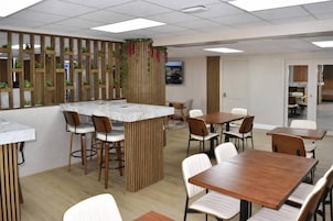 A modern dining area with a central island, wooden partitions, and white chairs.