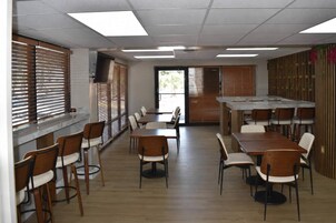 Un salón de conferencias con mesas y sillas, una televisión y ventanas con persianas.