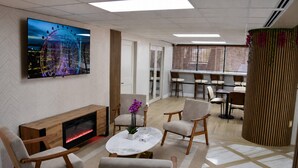 Eine moderne Lounge mit Kamin, bequemen Sitzgelegenheiten, einem Fernseher und einer Zierpflanze.