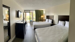 Ein Hotelzimmer mit zwei Betten, einem Schreibtisch, einem Fernseher und einem Balkon mit Blick.