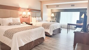 A hotel room with two beds, a desk, a chair, and a television. - Clayton Plaza Hotel & Extended Stay (St. Louis)
