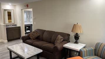 A living room with a brown sofa, a marble coffee table, a striped armchair, and a lamp.