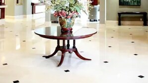 A lobby with a chandelier, a round table with a floral arrangement, and a painting on the wall. - Clayton Plaza Hotel & Extended Stay (St. Louis)