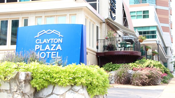 The Clayton Plaza Hotel sign with a stone wall and plants in front. - Clayton Plaza Hotel & Extended Stay (St. Louis)