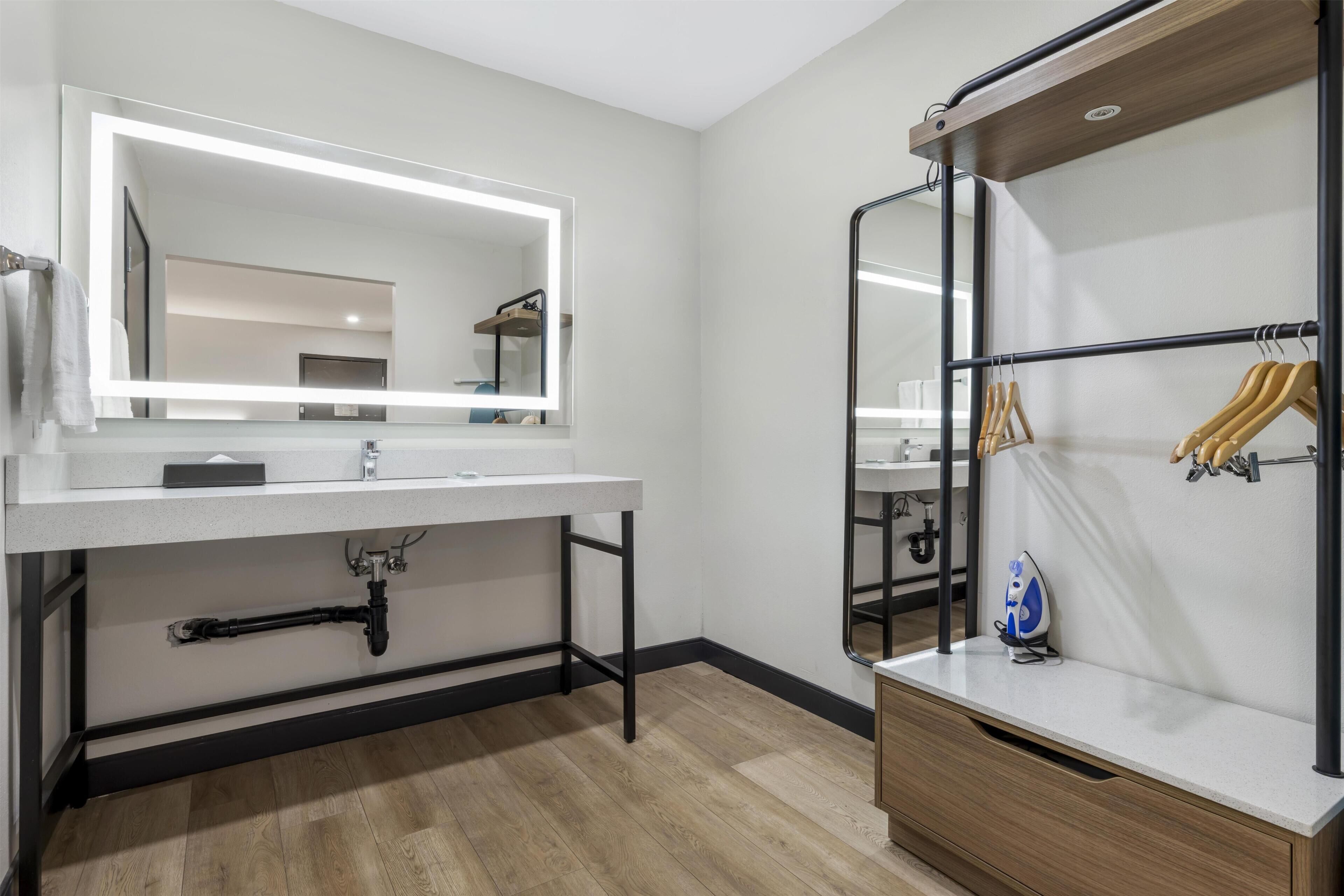 Une salle de bain moderne avec un grand miroir, un meuble-lavabo, un plancher en bois et un porte-serviettes.