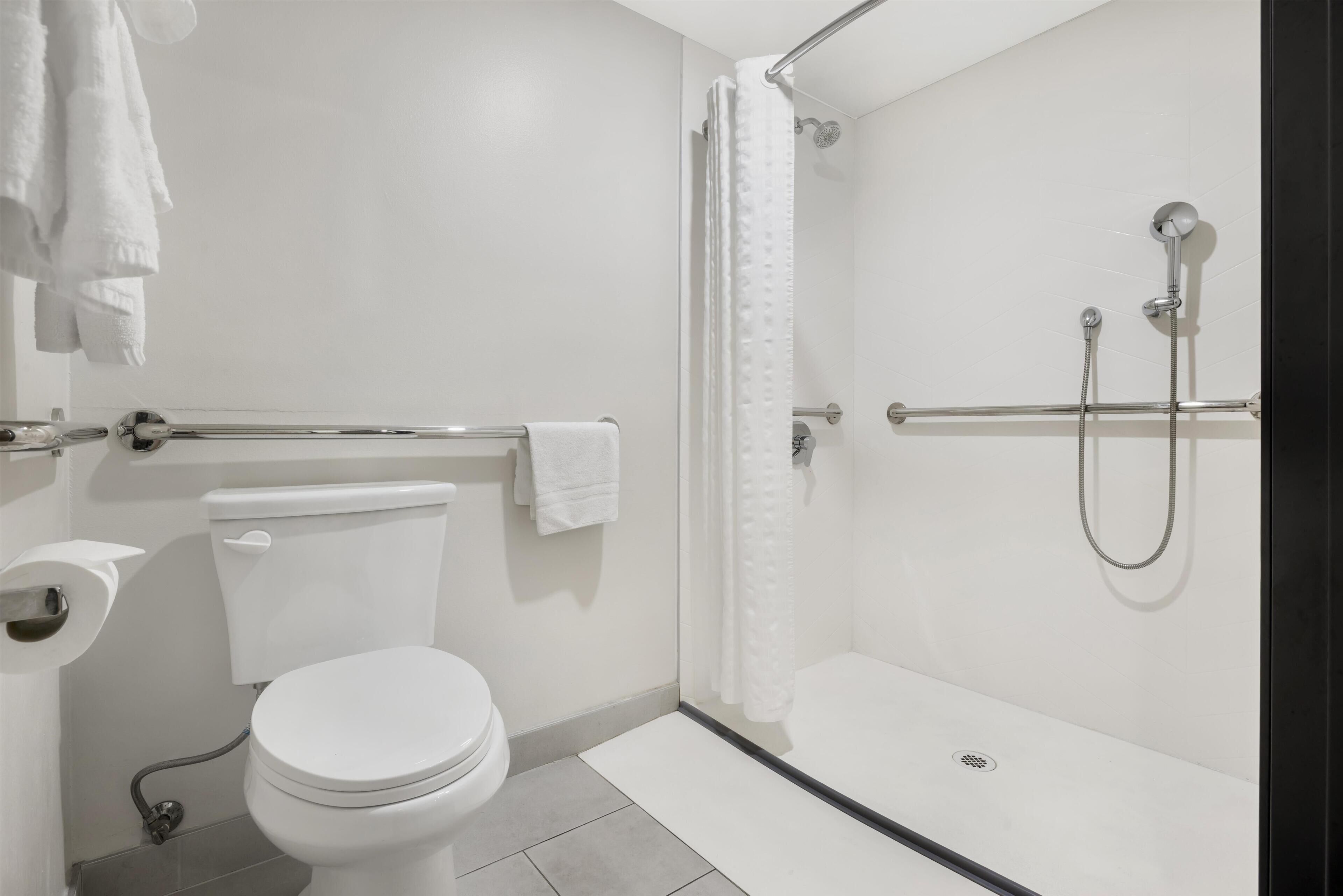 A modern bathroom with a toilet, shower, and a towel rack.