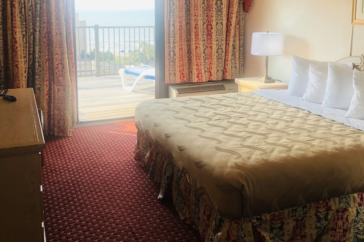 Une chambre d’hôtel avec un grand lit, un bureau, une lampe et une vue sur l’extérieur.