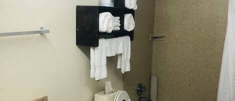 A bathroom with a toilet, sink, and bathtub. There are towels hanging on a rack.
