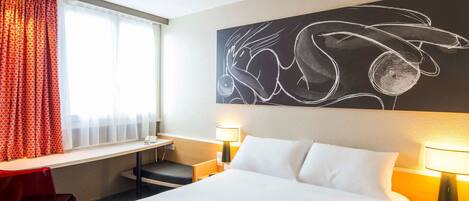 Una habitación de hotel con cama, escritorio, silla y una obra de arte en la pared.