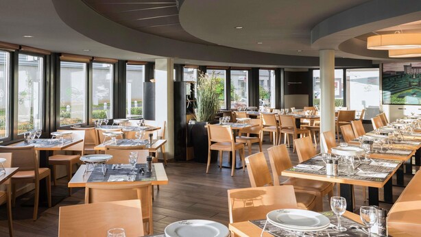 A restaurant with multiple tables set for dining, large windows, and a modern interior design. - ibis Tours Nord (Tours)
