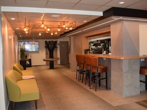 A modern bar area with stools, a counter, and a seating area with chairs.
