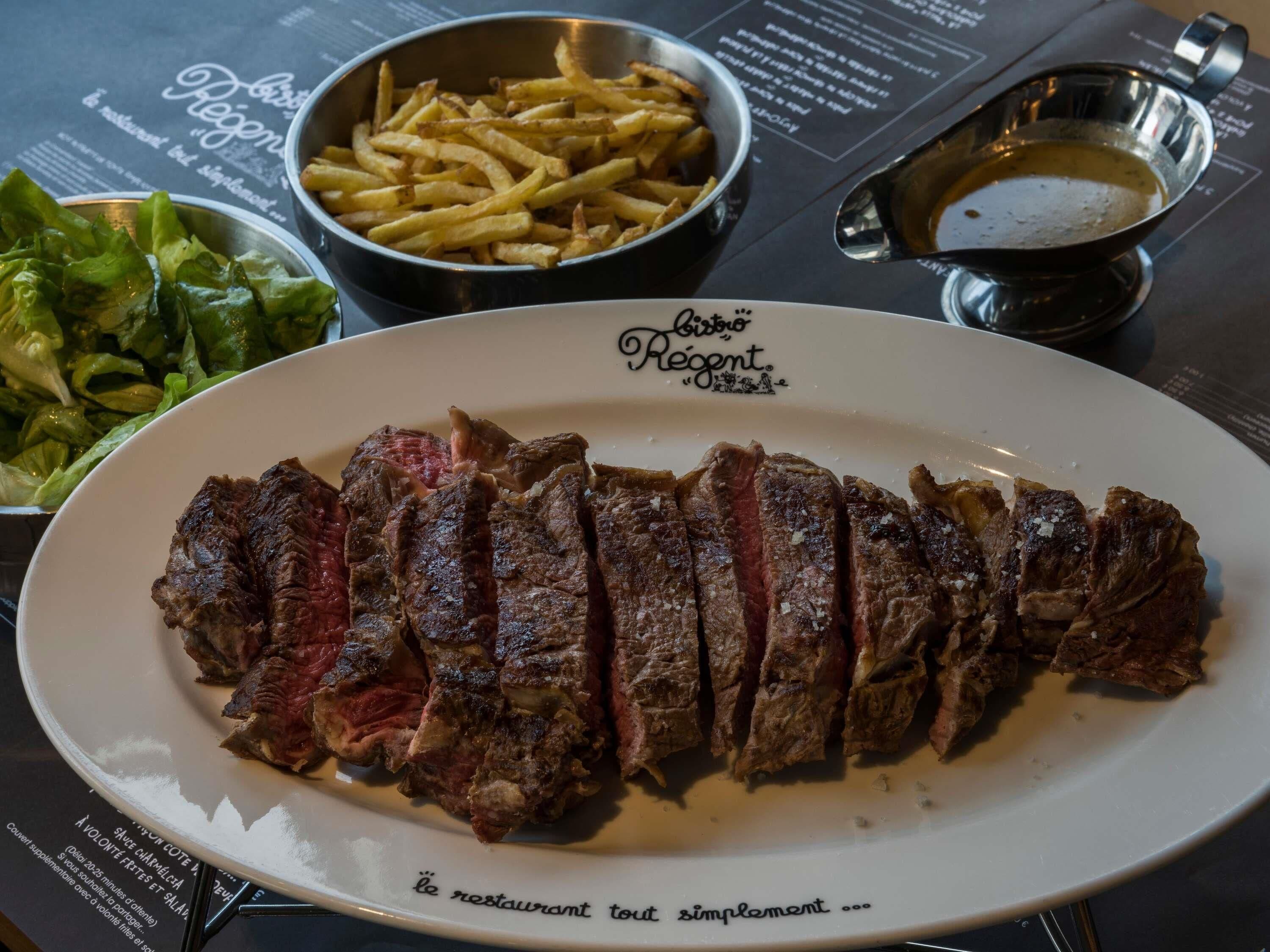 Un plato de bistec en rodajas acompañado de papas fritas y ensalada.