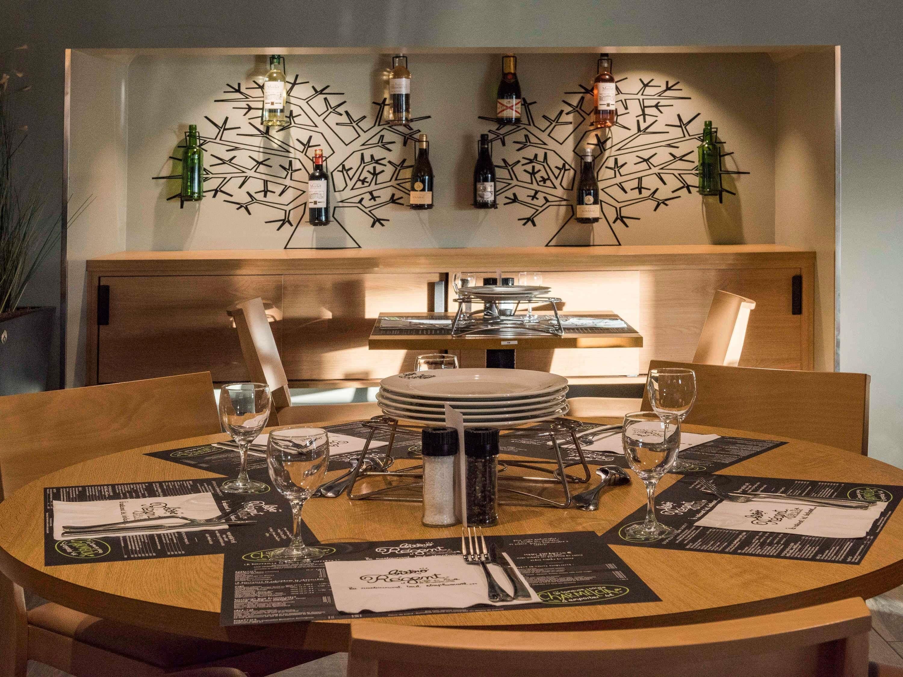 A dining table set with plates, cutlery, and wine glasses, with a wine rack in the background.