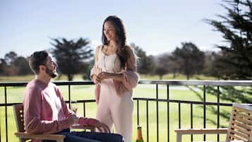 Un hombre y una mujer en un balcón con vistas a un campo de golf.