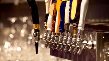 Um bar com várias torneiras de cerveja e dois copos de cerveja no balcão.