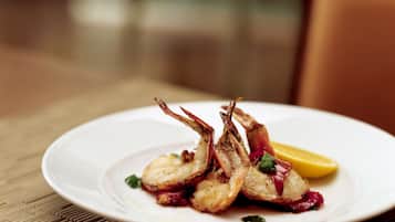 A plate of cooked seafood, possibly shrimp, with a lemon wedge on a white plate.