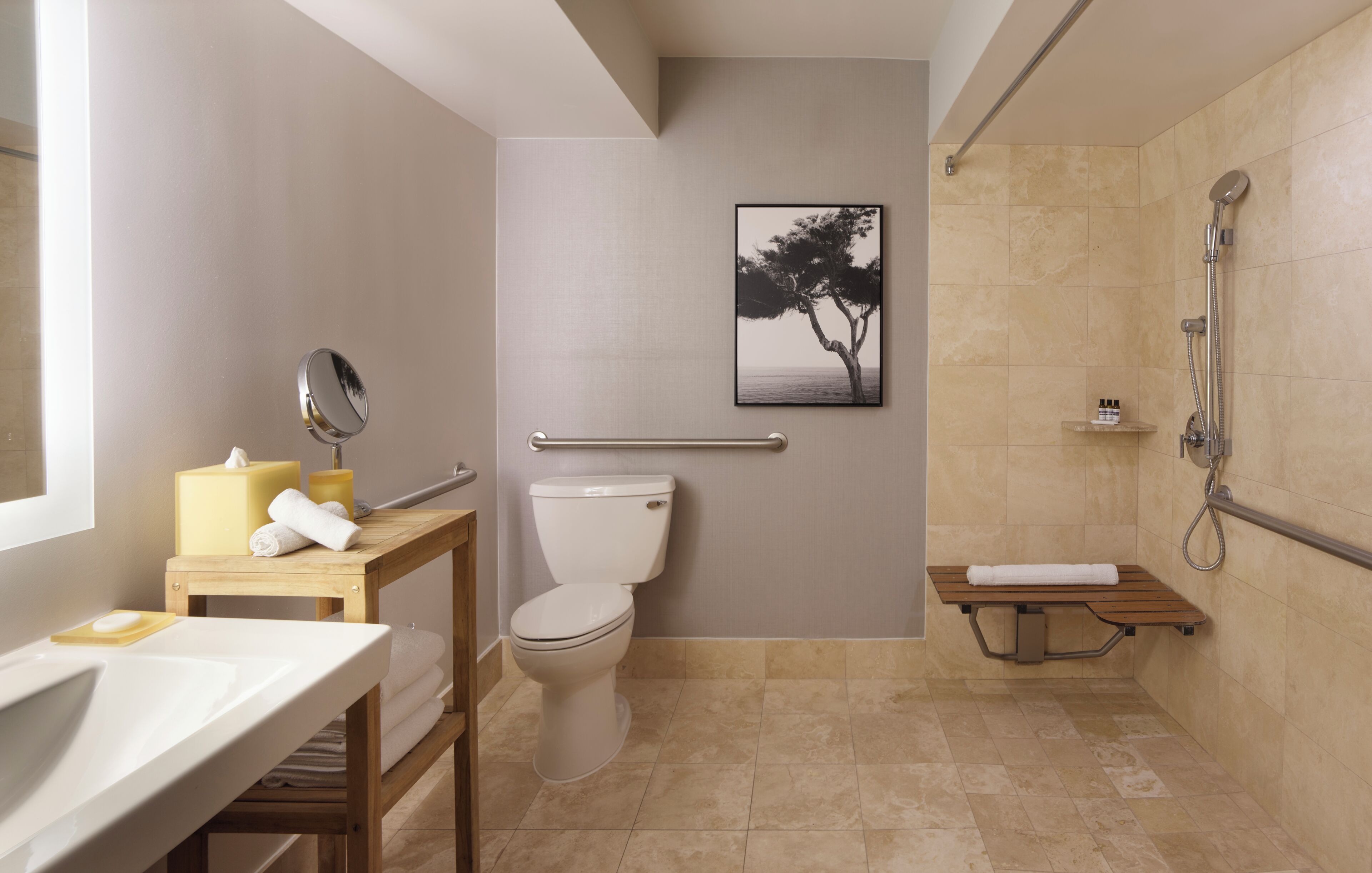 A bathroom with a toilet, sink, mirror, shower, and a framed picture on the wall.