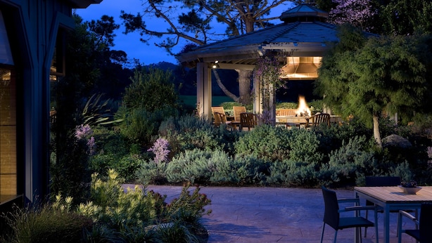 Un belvédère doté d’un foyer, entouré d’une végétation luxuriante et agrémenté d’un espace patio avec des meubles d’extérieur.