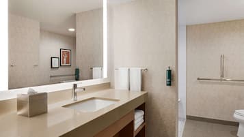 A modern bathroom with a large mirror, two sinks, a toilet, and a shower area.