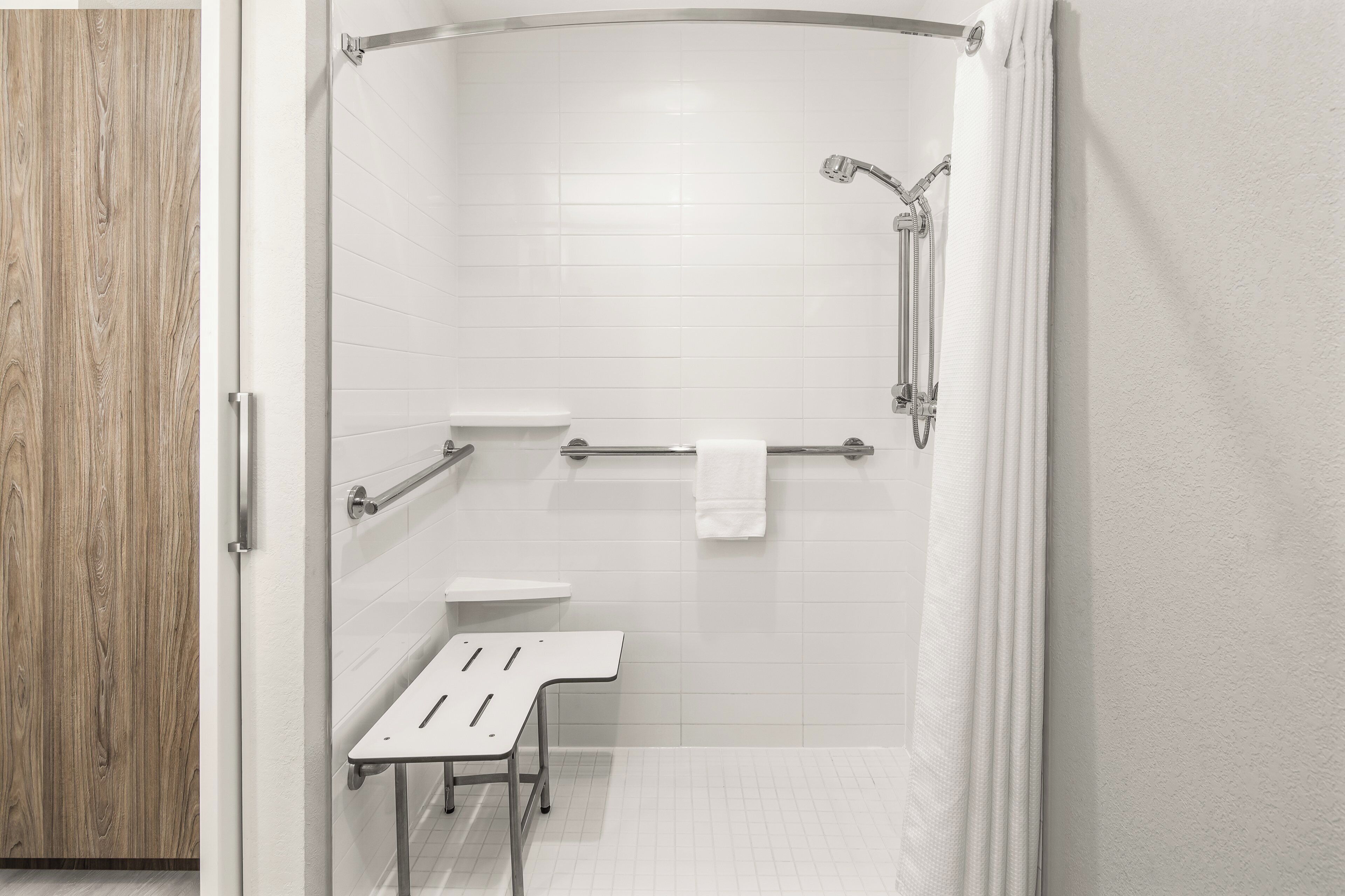 Une salle de bain moderne équipée d’une douche, de toilettes et d’un banc.