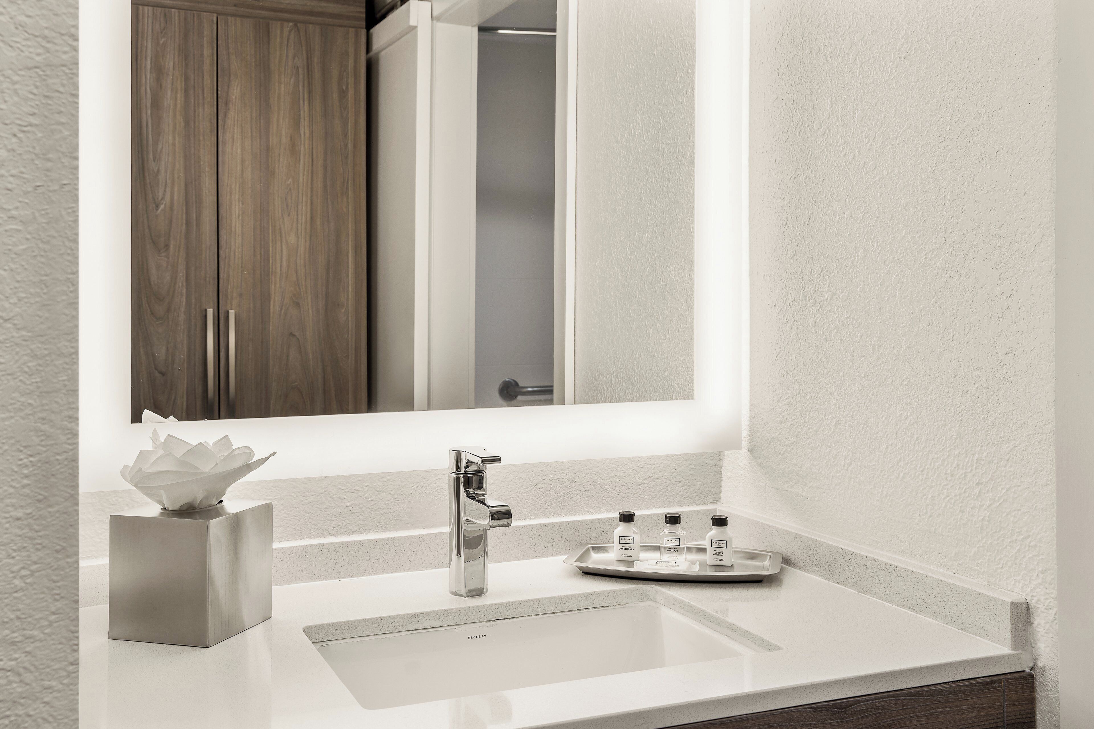 Un baño moderno con un lavamanos blanco, un espejo y un mueble de madera.