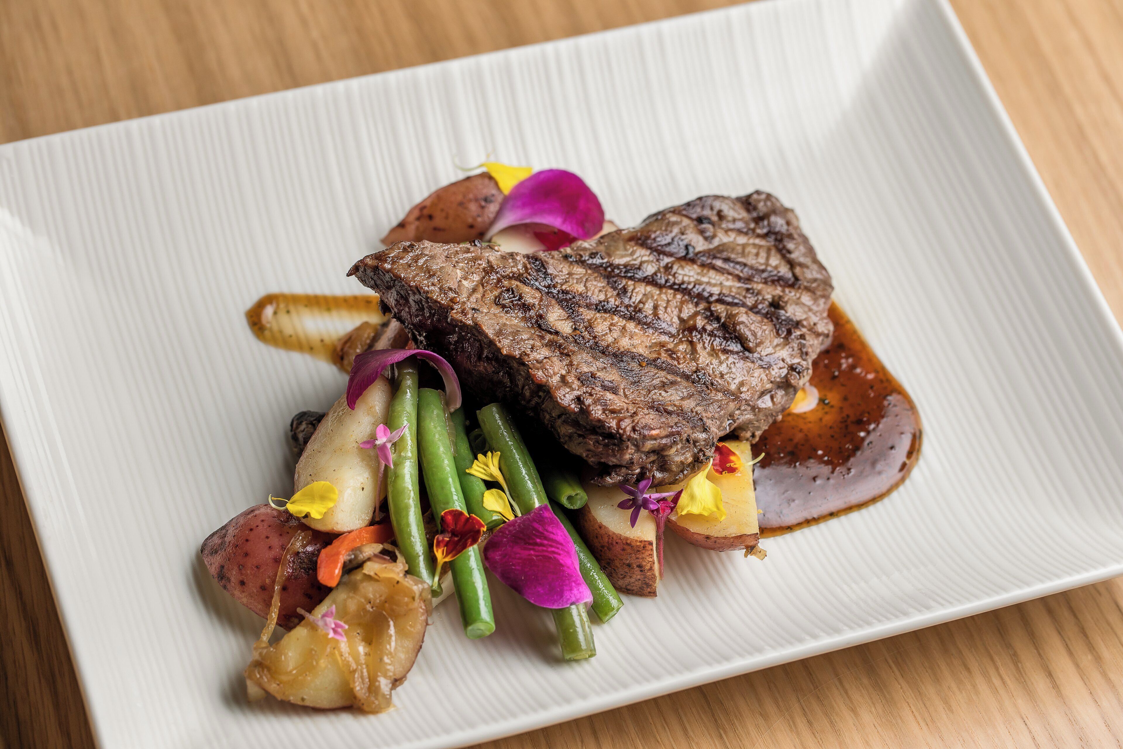 A steak with vegetables and sauce on a plate.