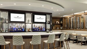 A bar area with a counter, bar stools, and a display of liquor bottles. - Crowne Plaza Orlando - Lake Buena Vista  by IHG (Orlando)