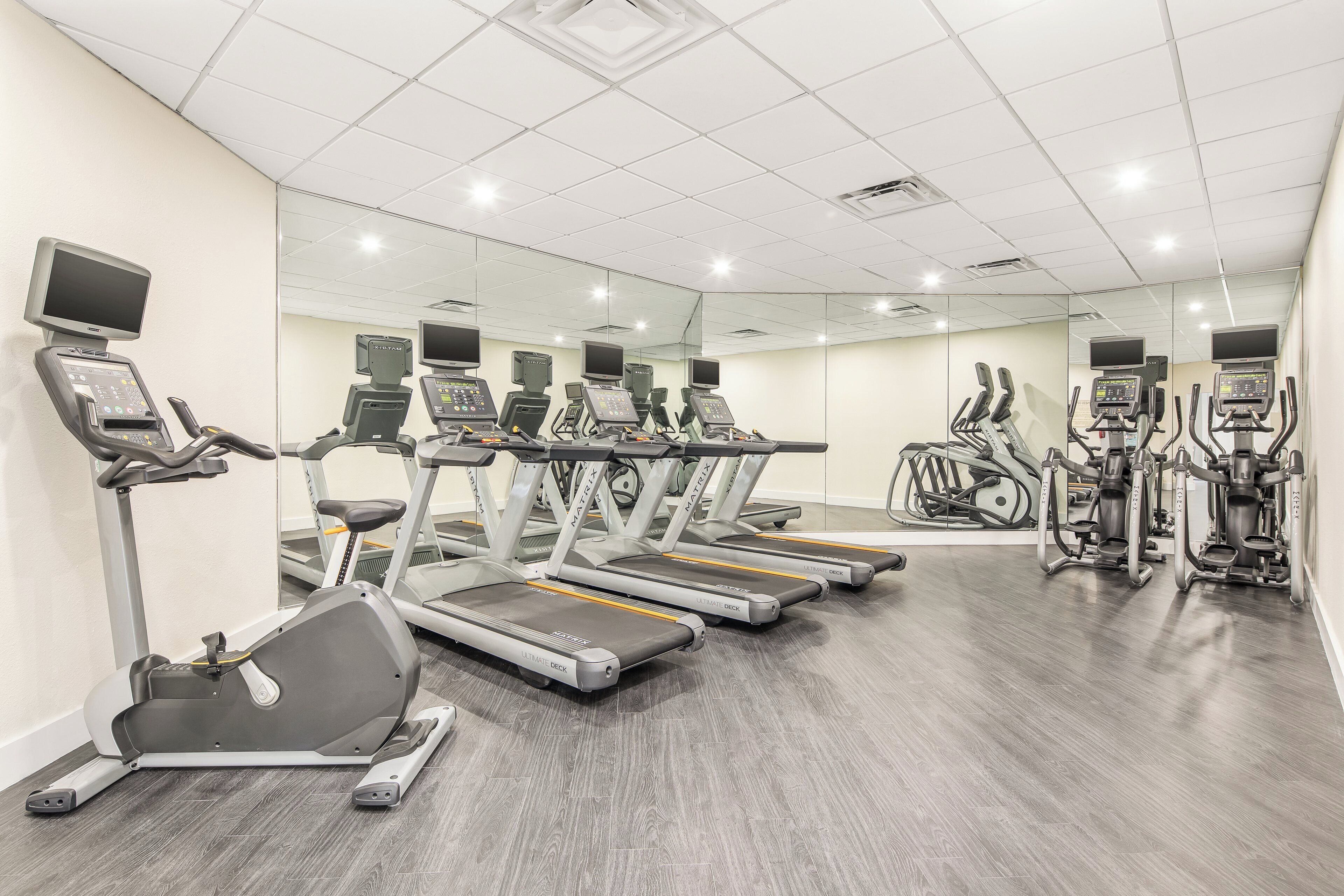 Un gimnasio con cintas de correr, elípticas y bicicletas estáticas.