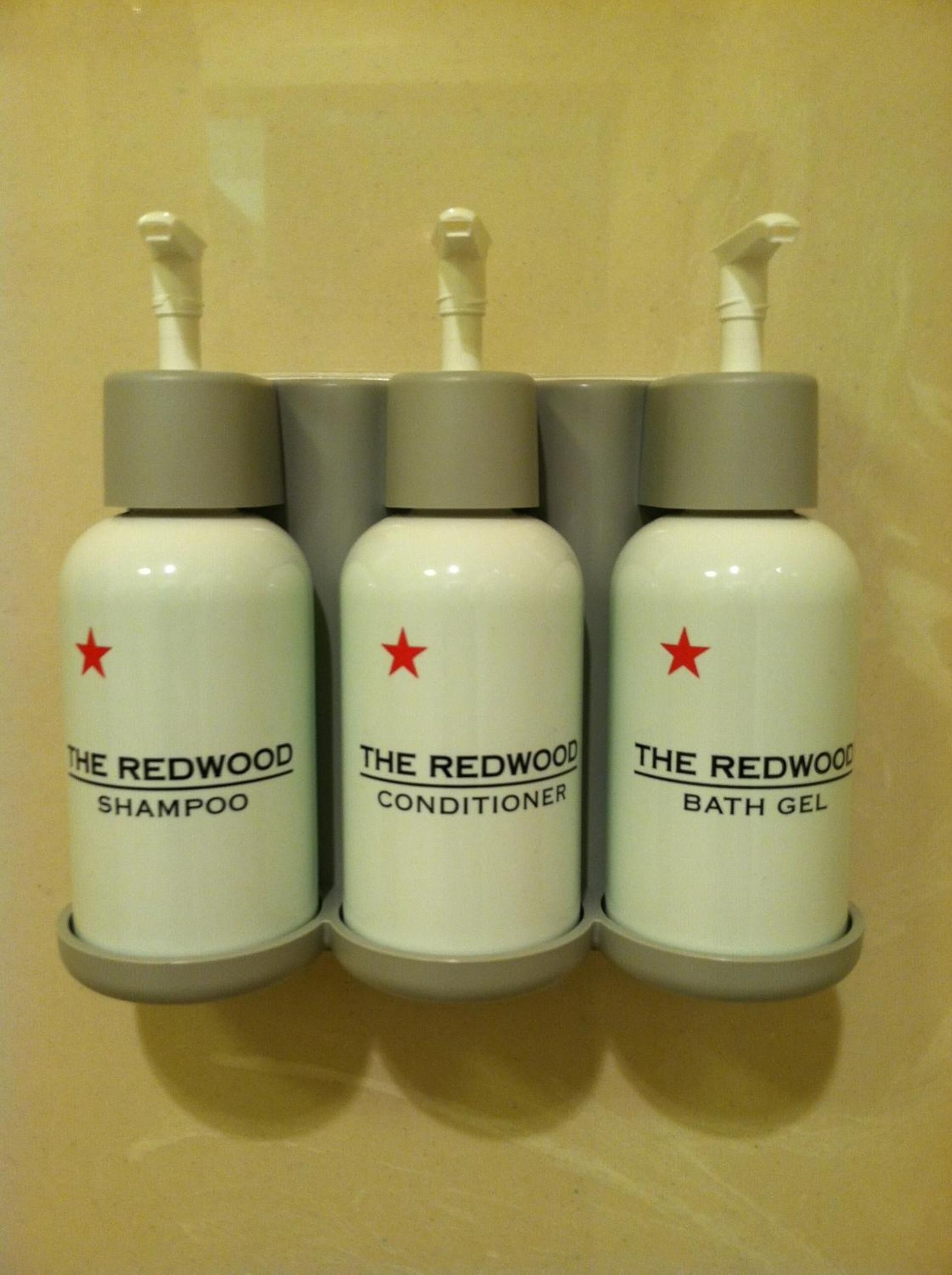 Trois flacons de produits de la marque The Redwood : un shampooing, un après-shampooing et un gel douche.