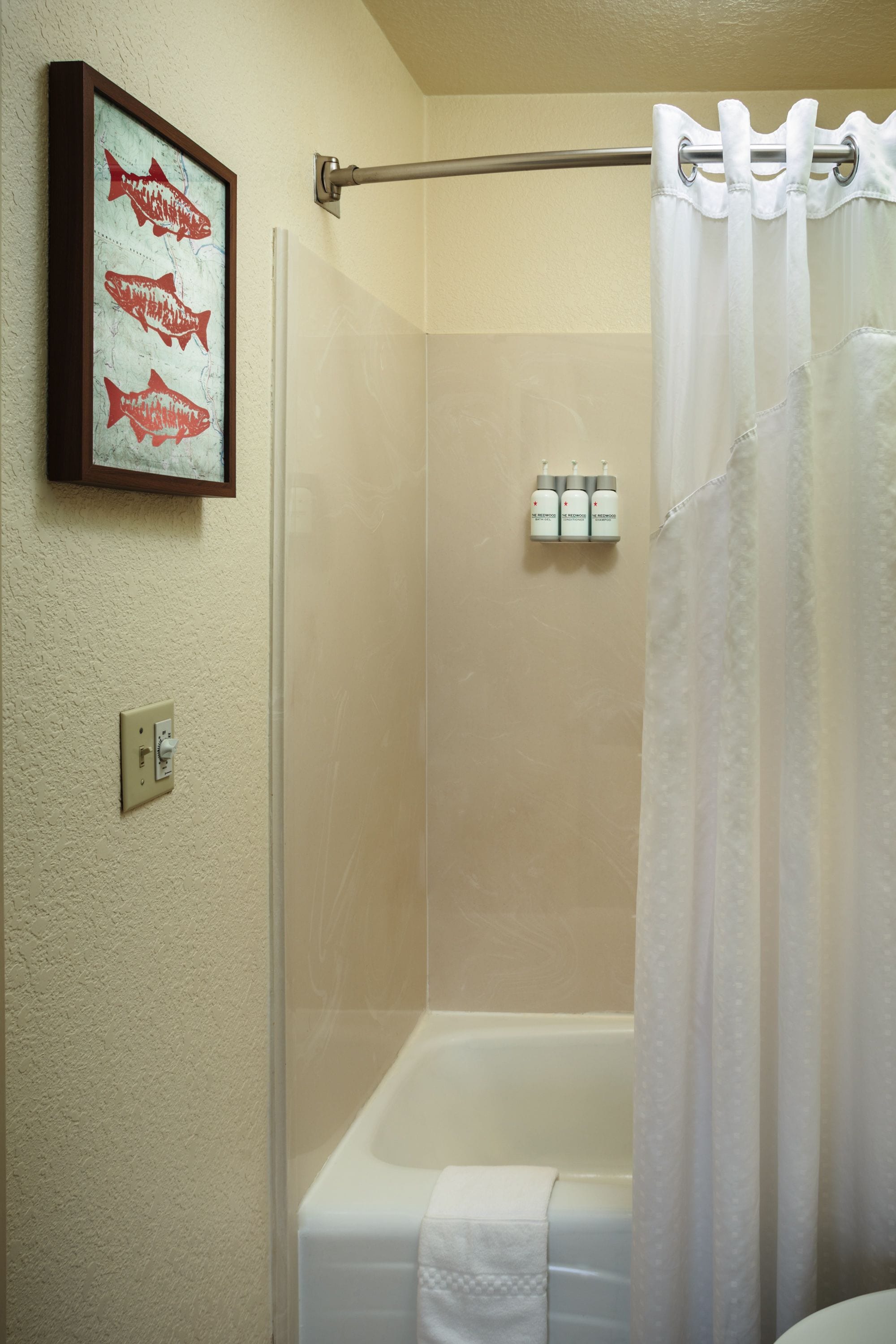 Une salle de bain avec une baignoire, un rideau de douche, un porte-serviettes et un tableau encadré au mur.