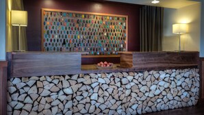 Un comptoir d’accueil avec un plateau en bois, un présentoir mural où sont exposés divers objets, et une pile de bois de chauffage à la base.