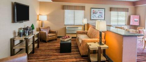 A hotel lobby with a seating area, a reception desk, and a television.