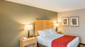 A hotel room with a bed, two bedside tables, a lamp, and two framed pictures on the wall.
