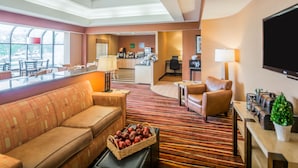 A hotel lobby with a sofa, chairs, a coffee station, and a TV. - Comfort Inn - NYS Fairgrounds (Syracuse)