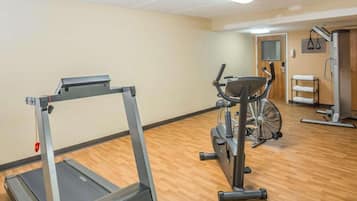 A gym with a treadmill, stationary bike, and weight machine.