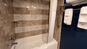 Une salle de bain avec une baignoire, un rideau de douche et un porte-serviettes avec des serviettes.