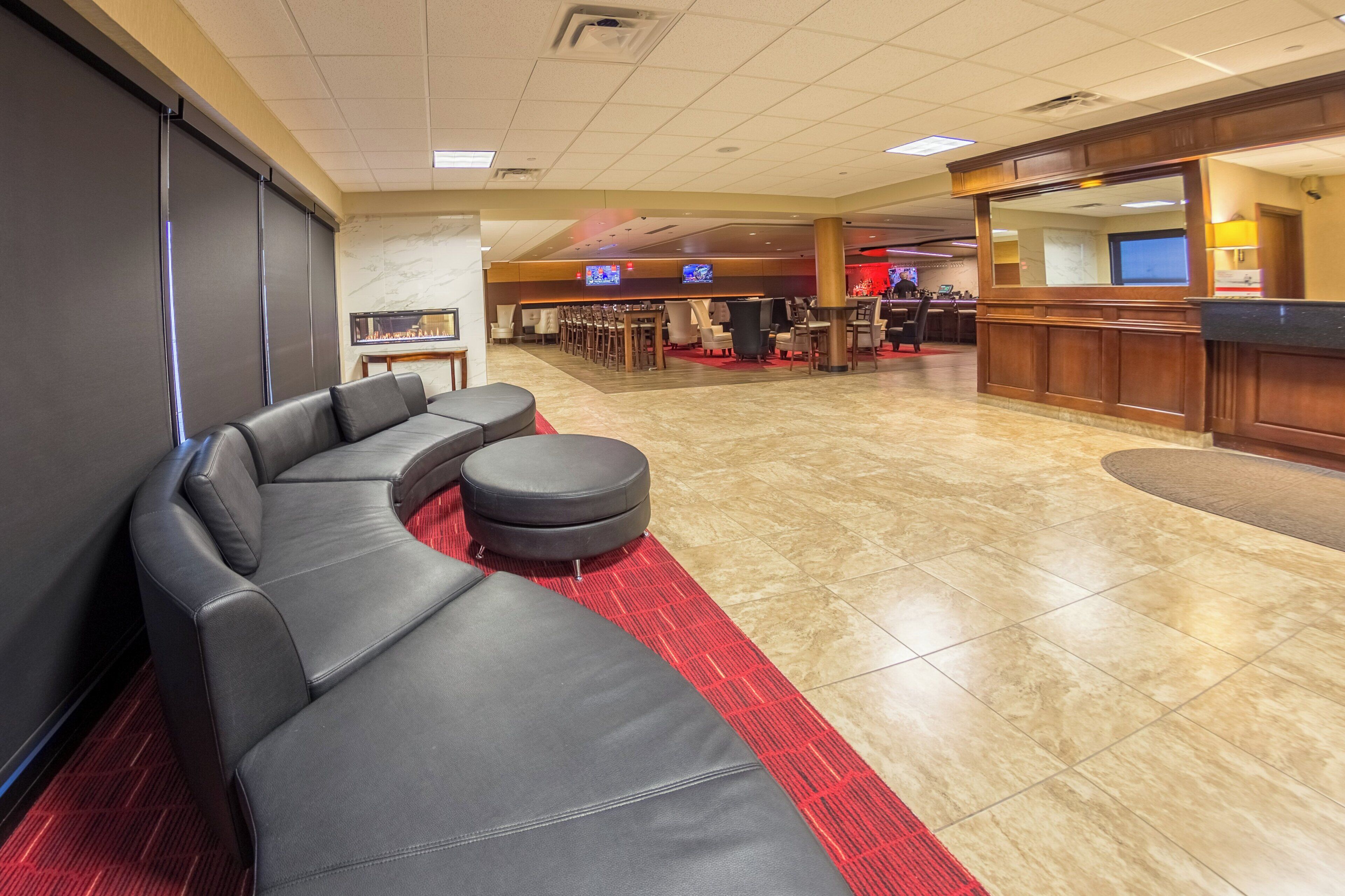 A hotel lobby with a black leather sofa, a red carpet, and a reception desk.