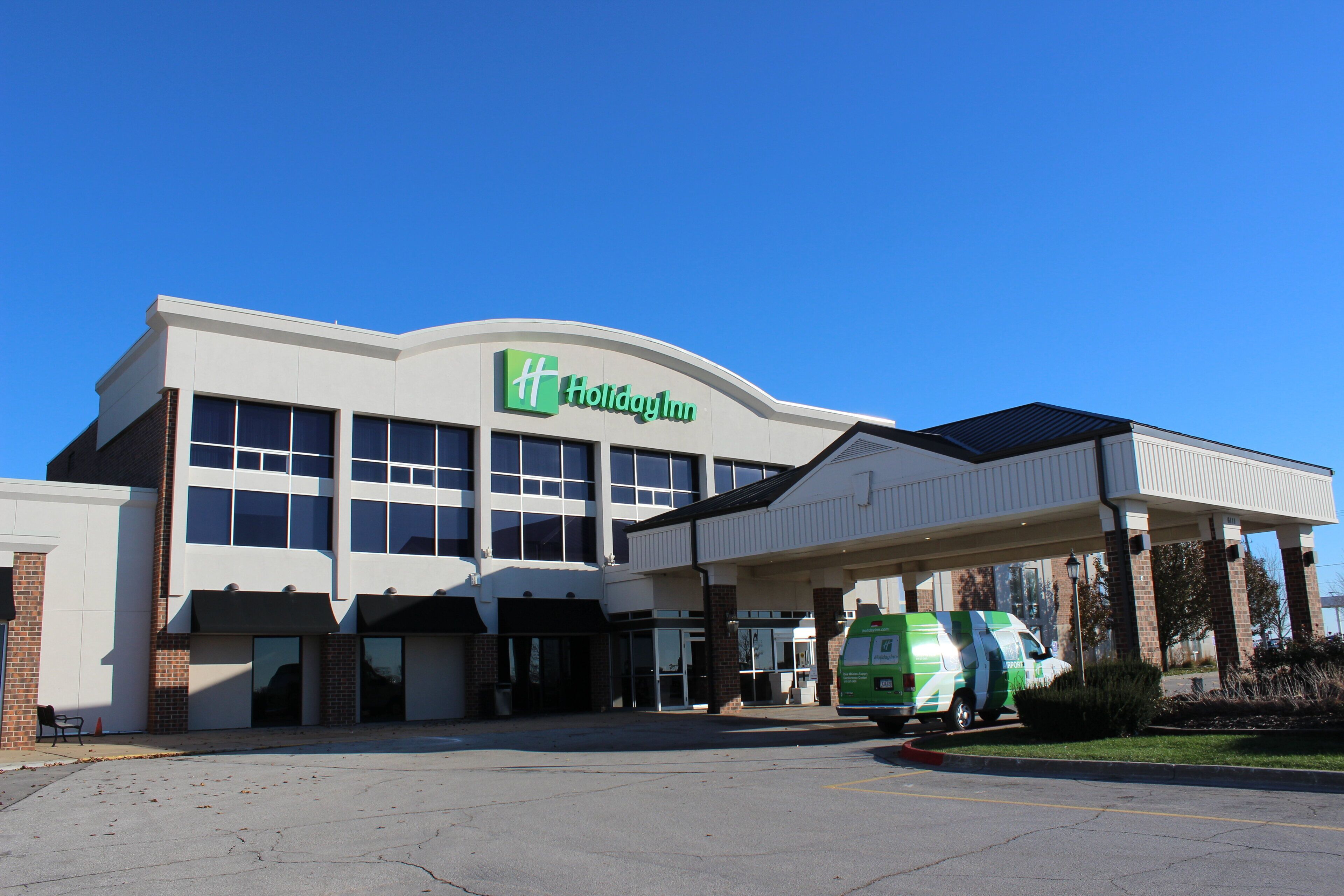 Un bâtiment de la chaîne Holiday Inn Express doté d’un parking couvert et d’une navette verte.