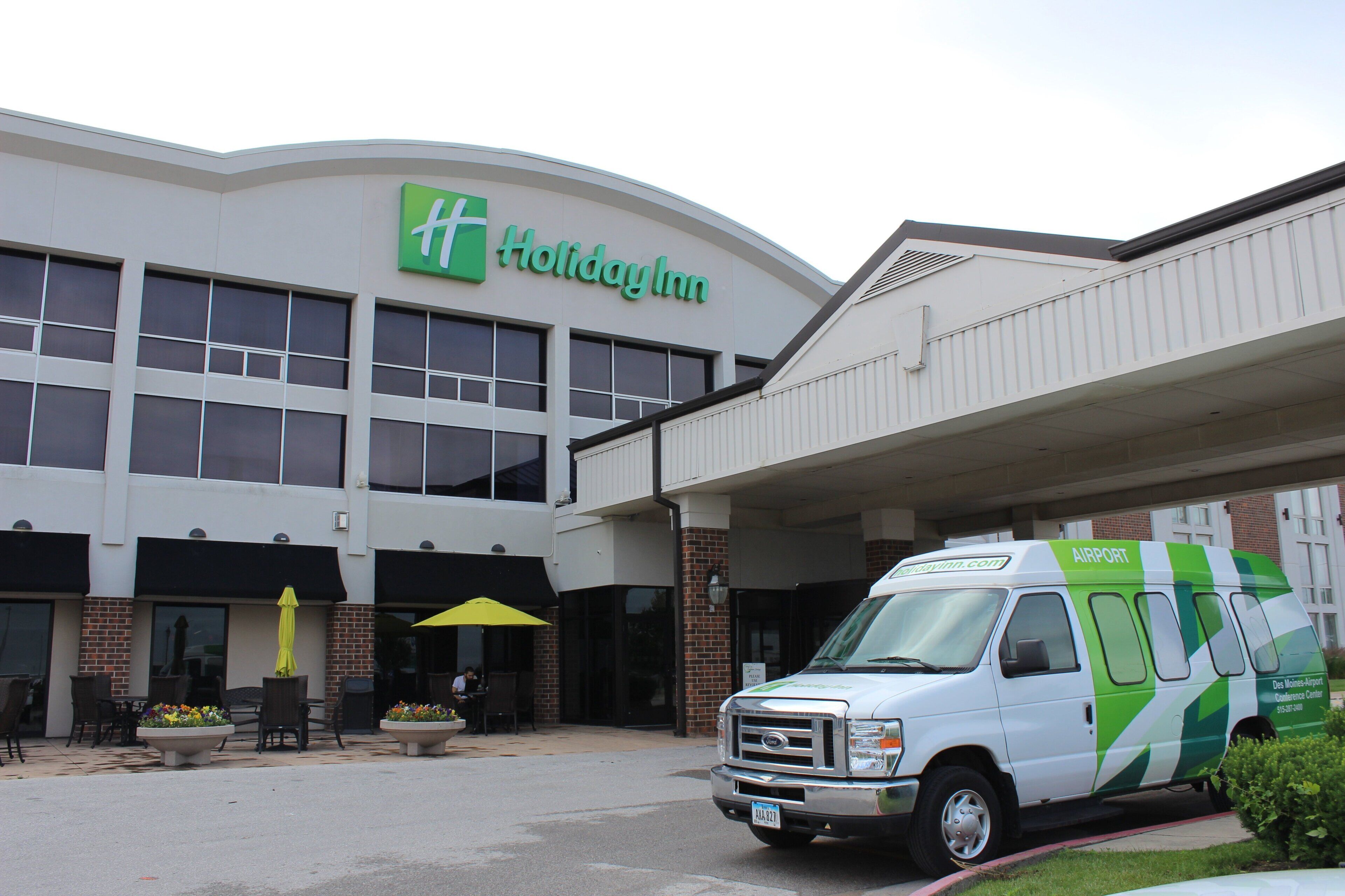 A Holiday Inn hotel with a green logo, a parking area, and a van with 'Airport' written on it.