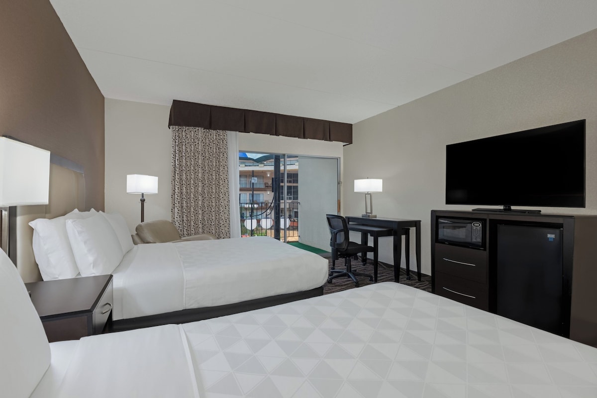 Quarto de hotel com duas camas, uma escrivaninha, uma televisão e um minibar.