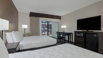 A hotel room with two beds, a desk, a television, and a minibar.