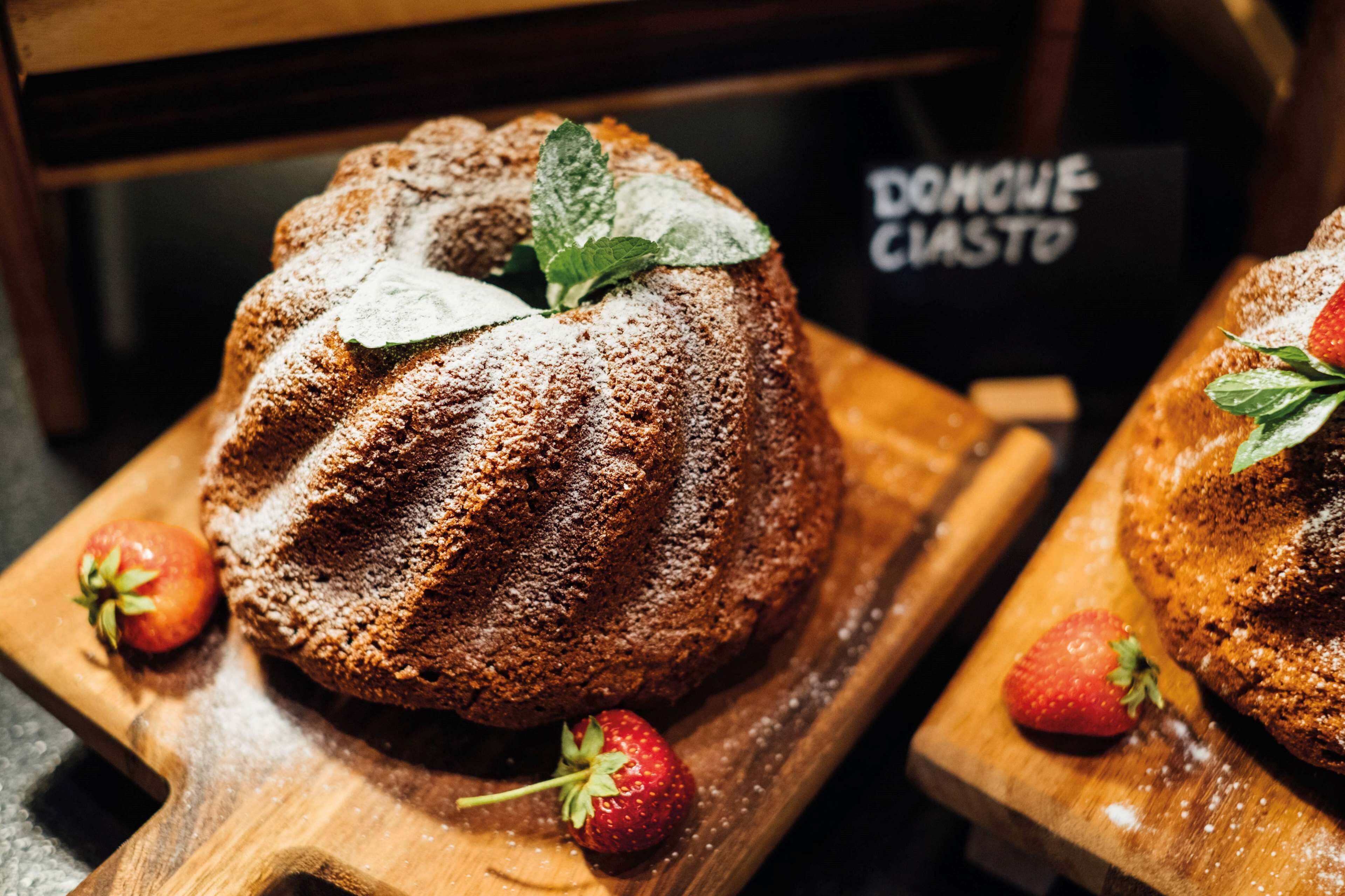 Un pastel Bundt con fresas y hojas de menta sobre una tabla de madera.