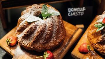 Un pastel Bundt con fresas y hojas de menta sobre una tabla de madera.