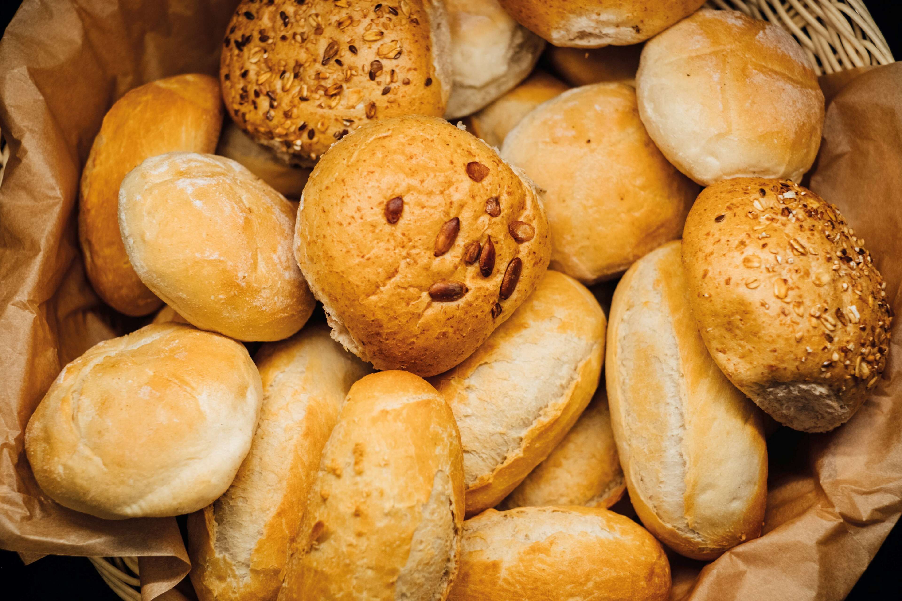 Ein Korb mit verschiedenen Brötchen, darunter einige mit Saaten und andere schlicht.