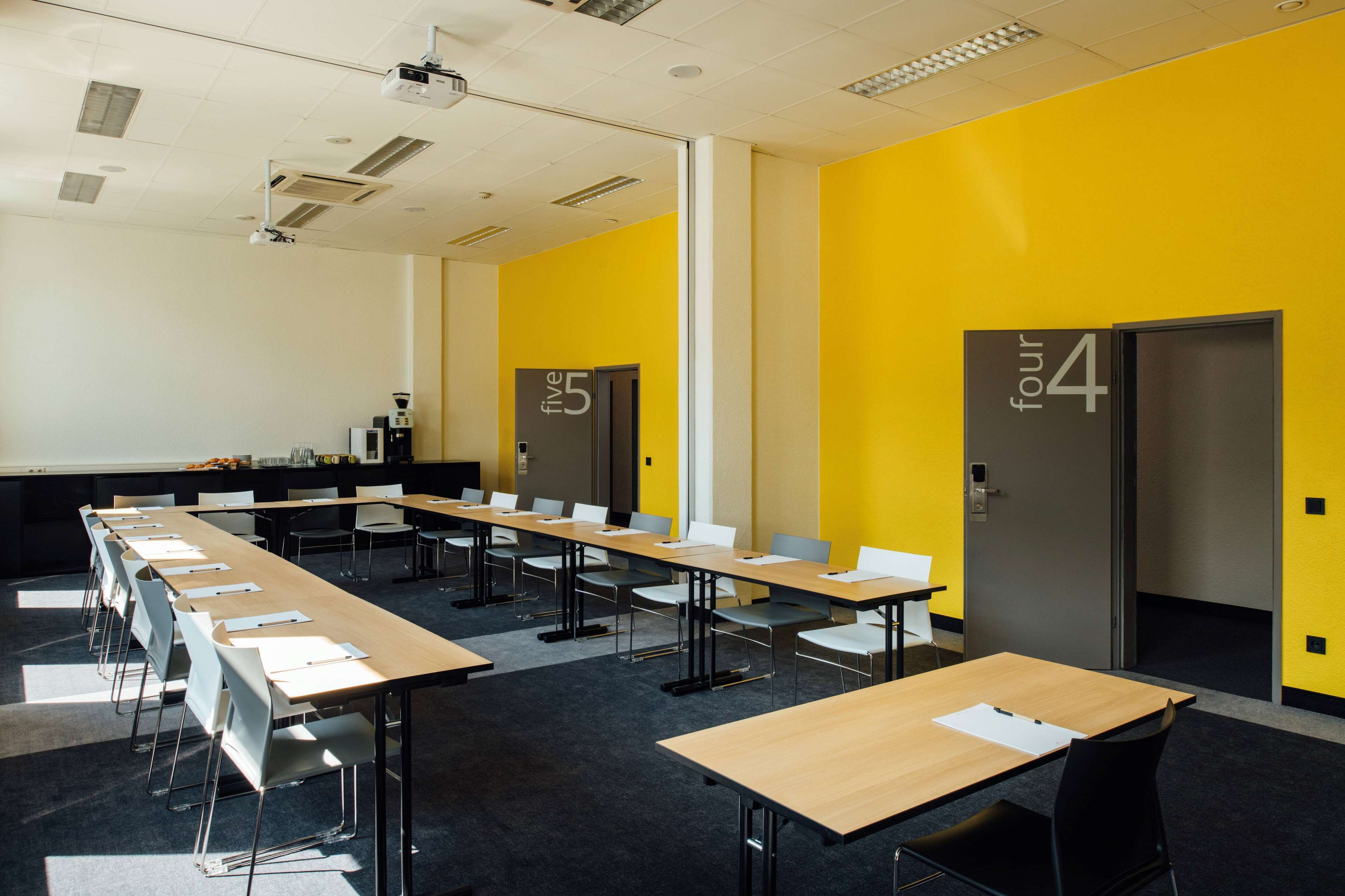 A conference room with multiple tables and chairs, a projector, and a presentation screen.