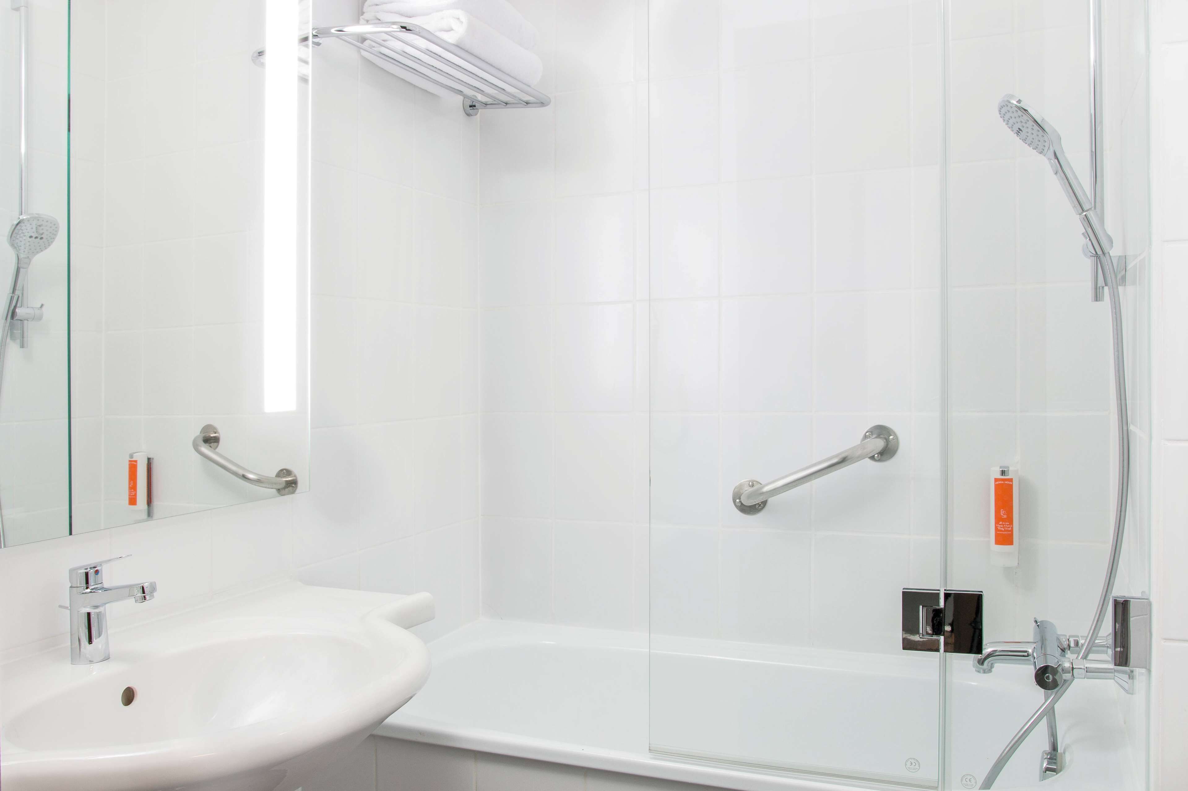 Une salle de bain moderne avec une douche à parois de verre, un lavabo blanc et une douchette à main.