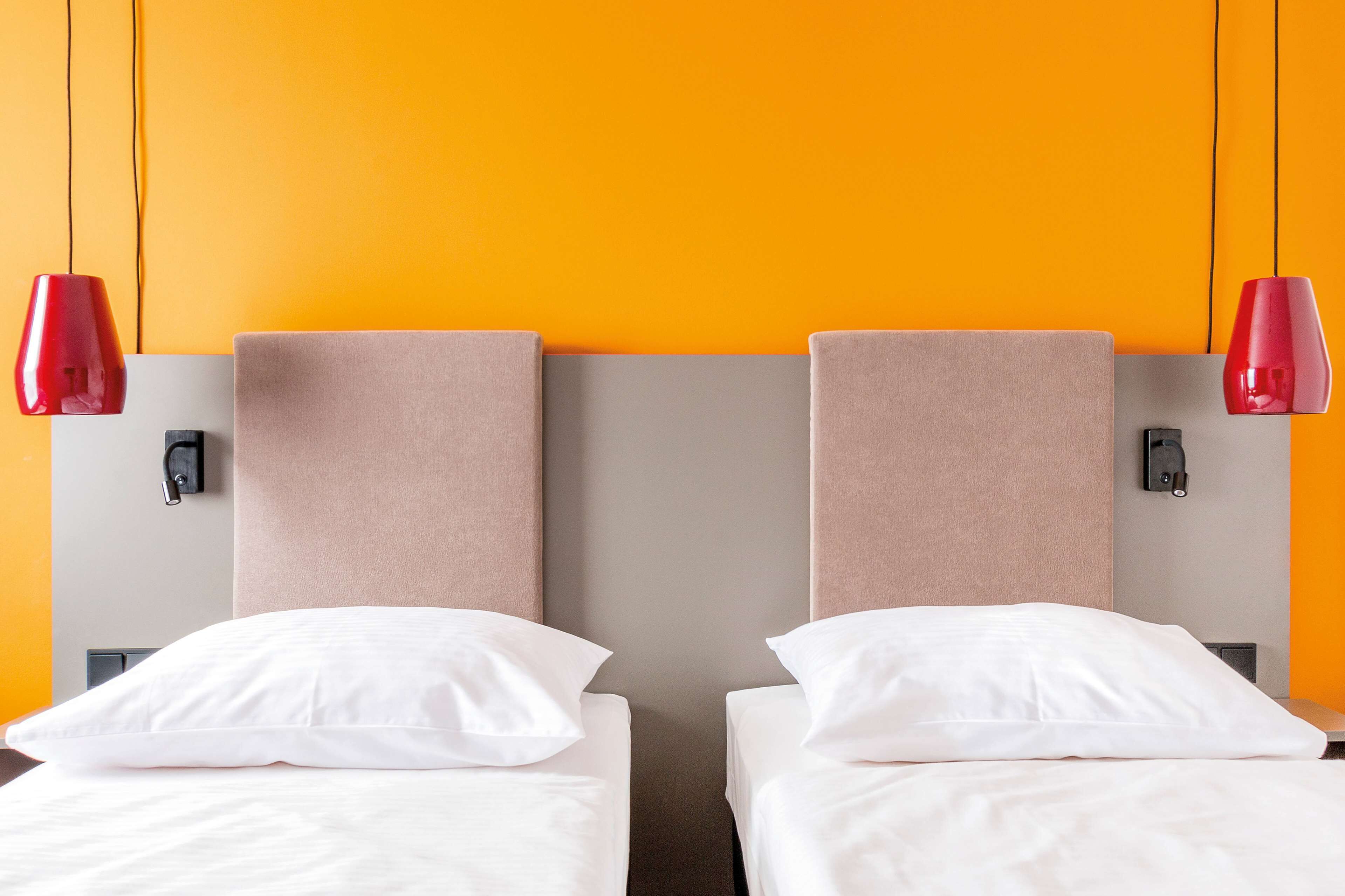 A hotel room with two beds, each with white bedding and a beige headboard.